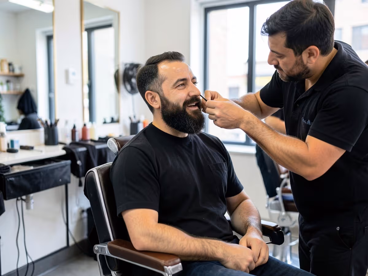 Barber trimming a bearded man's mustache in a barbershop chair