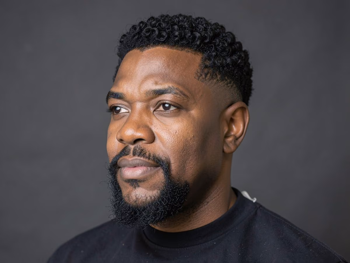 Man with a curly fade with goatee